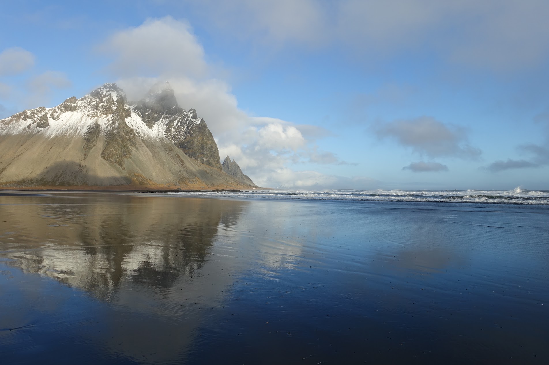 Mountain reflected on wet black sand beach on the south coast of Iceland.
